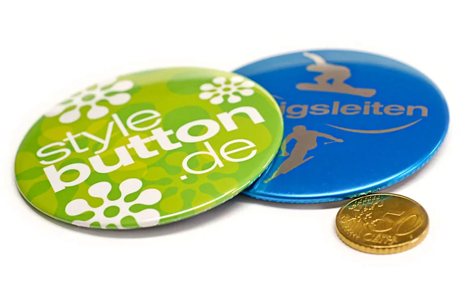 2 Stück 76 mm Buttons liegen zum Größenvergleich neben einer 50 Cent Münze